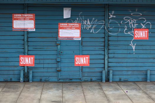 Lima, Peru - September 22, 2011: A shop in Miraflores, Lima closed by the SUNAT (National Supervision of Tributary Administration, Peru) for tributary infraction. The SUNAT signs on closed shops are an everyday sight in the Peruvian capital. 