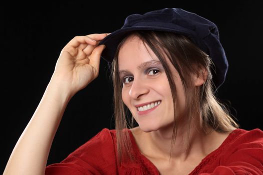 Portrait of a young Caucasian woman smiling wearing a red shirt and a blue Gatsby cap (Selective Focus, Focus on the left eye)