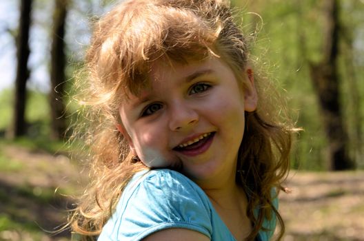 The photo shows a close-up of a happy, smiling and joyful girl during her playing with her sister in the park.