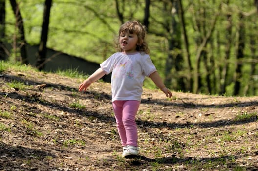 The photo shows a happy, smiling and joyful girl during her playing with her sister in the park.