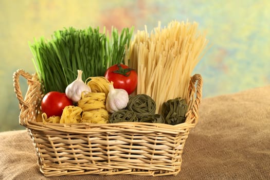 Raw green and yellow tagliatelle paglia e fieno (straw and hay) with raw tomatoes and garlic bulbs (Selective Focus, Focus on the ingredients in the front) 