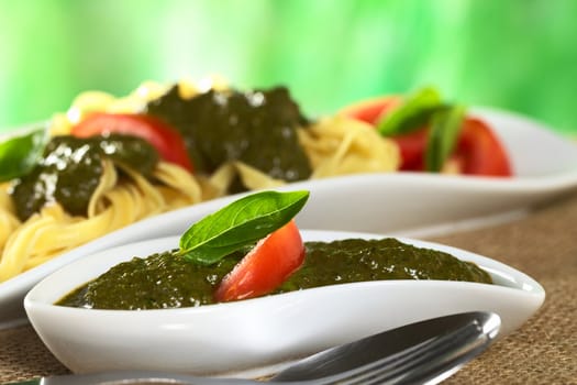 Fresh pesto made of basil and garlic garnished with fresh basil leaf and tomato slice (Selective Focus, Focus on the basil leaf)