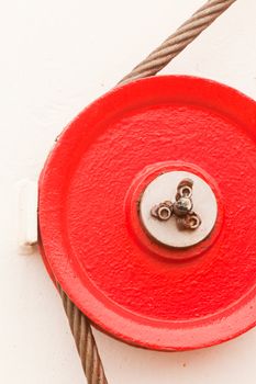 The red fairlead pulley has a grooved rim and is used as a guide around which the cable can pass in order to change direction of the pull on the load