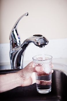 Thirsty man filling a glass of water