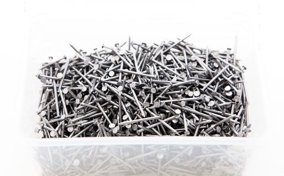 many metal nails in transparent box over white background