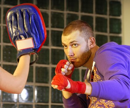 young adult man boxing in gym with his trainer