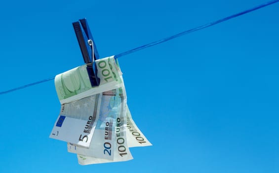 concept of  money hanging on clothesline against blue sky