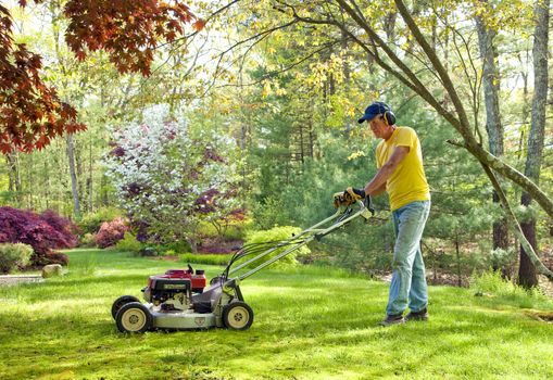 Older man mowing the lawn in the spring