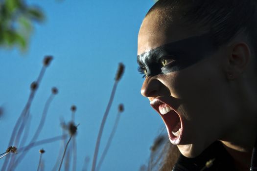 PORTRAIT OF THE GIRL WITH DRAWN IN THE FACE OF THE BLACK BANDAGE. SHOOTING WITH RIGID LIGHT AT NIGHT, IN THE FIELD AGAINST THE SKY