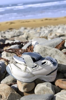 abandoned running shoe on a rocky stone beach in Ireland