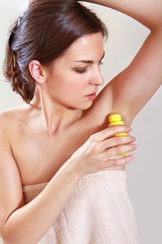 beautiful woman applying roll-on antiperspirant