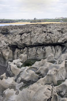 strange rock formations on the beach in ballybunion county kerry ireland with town and castle in background