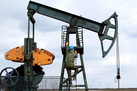 oil worker climbs to the pumpjack