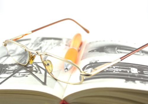 Old book, glasses and pen. Shallow DOF.