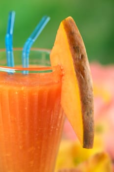 Fresh papaya juice garnished with a papaya slice (Selective Focus, Focus on the front edge of the papaya slice and the front rim of the glass) 