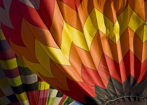 Muli-colored hot air balloons seen closeup while being blown up.