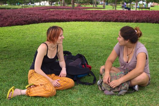 Two young women (one Peruvian, the other European) talking in a park in Miraflores, Lima, Peru 