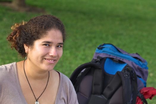 Young smiling Peruvian woman with backpack in park (Selective Focus, Focus on the eyes of the woman)