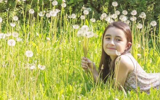 Little girl blowing dandelions, nine at the same time