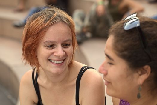 Young Caucasian woman talking to a young Peruvian friend (Selective Focus, Focus on the eyes of the Caucasian woman) 