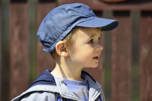 The picture shows a little boy who stood in play against the fence in the backyard.