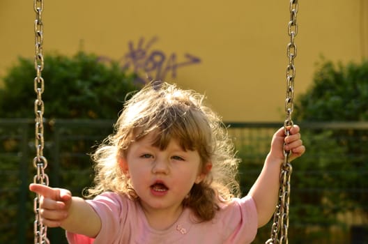 Photo shows a little girl on a swing at the playground in the park That shows who has her swing.