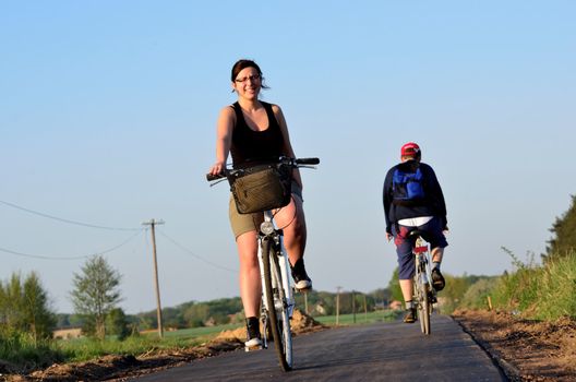 Photo shows a young woman on a bicycle passes an unknown man on a bicycle path.