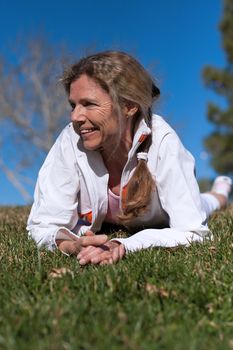 mature woman laying in grass in a park smiling