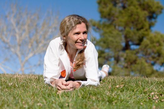 mature woman laying in grass in a park smiling
