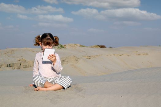 little girl with tablet pc in desert