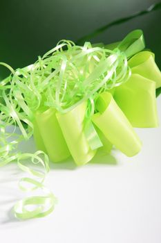 Decorative green ribbon tied in an ornamental bow with twirled streamers lying ready to be added to a luxury gift