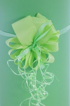 Beautiful ornamental green ribbon bow with decorative twirled streamers below on a green gift