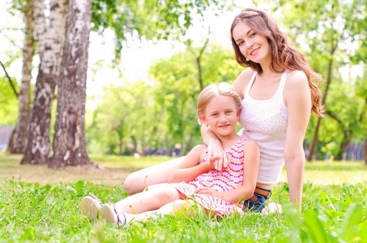 mother and daughter sitting together on the grass, and spend time with family