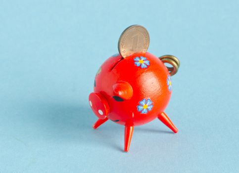 Red piggybank on blue background. Saving money for black day in pig money-box. Nest-egg. Pfennig.