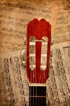 Top off a guitar resting against music notes.