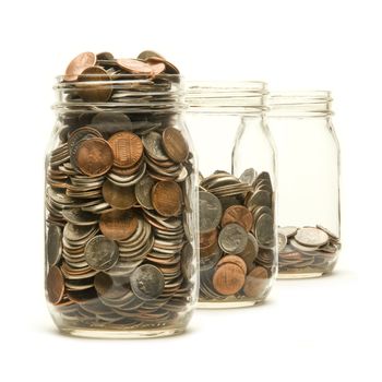 Three glass jars filled with American coins to different levels against a white background