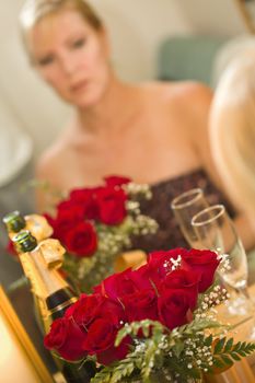 Attractive Pensive Blonde Sits at Mirror Near Champagne and Roses.