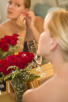 Attractive Blonde Woman Applies Her Makeup at a Mirror Near Champagne and Roses.