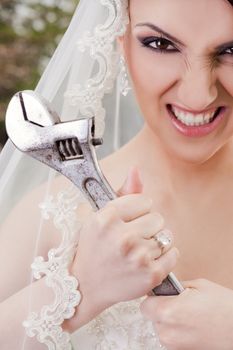 Close-up of furious bride holding monkey wrench, looking at camera