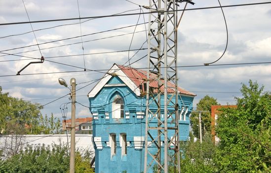 The blue and beautiful house with white frames of windows behind electric wires after a rain