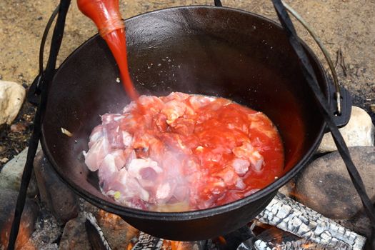 preparing osso buco outdoor in traditional cauldron