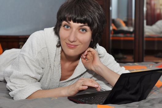 Young woman lying in the bed with laptop