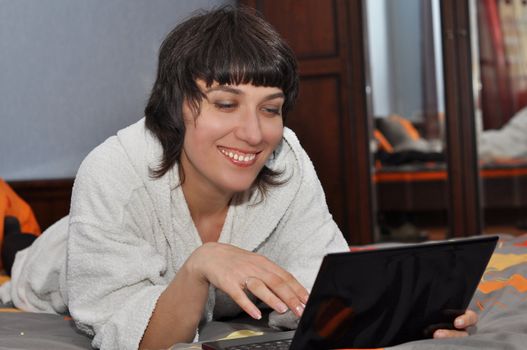 Young woman lying in the bed with laptop