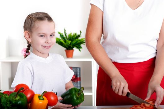 Mother and daughter cooking vegetable salad together