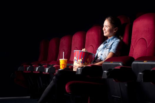 young woman sitting alone in the cinema and watching a movie