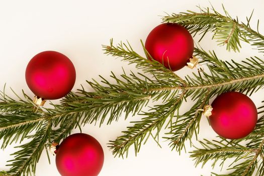 Border of red christmas garland with baubles and ribbons on white.