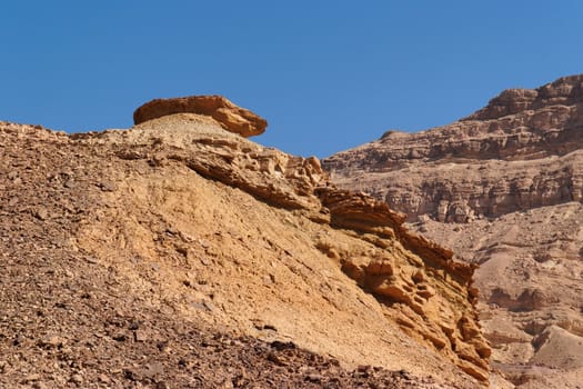 Weathered orange rock on top of dune in desert canyon