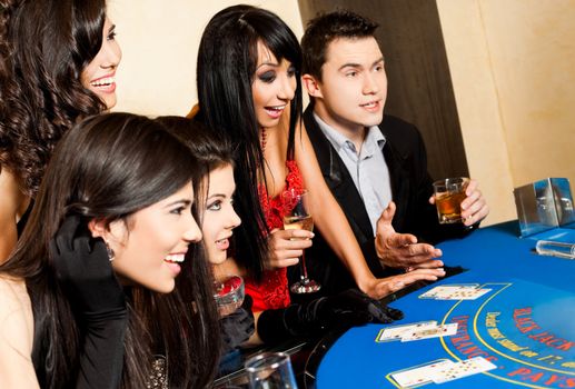 Group of young happy people sitting in casino behind black jack table