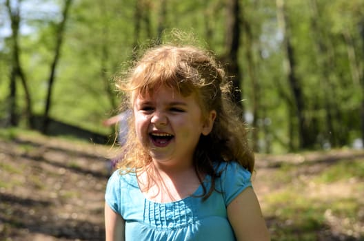 The photo shows a happy, smiling and joyful girl in the park.