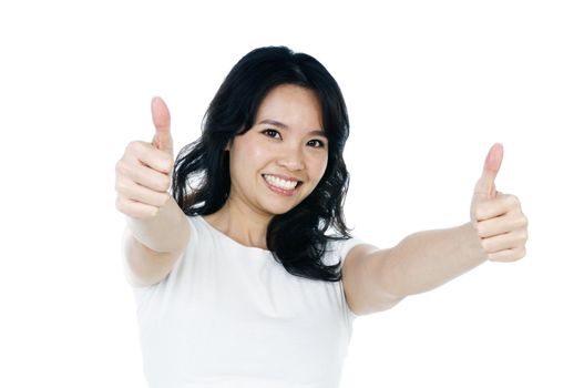 Portrait of an attractive young woman giving thumbs up against white background.